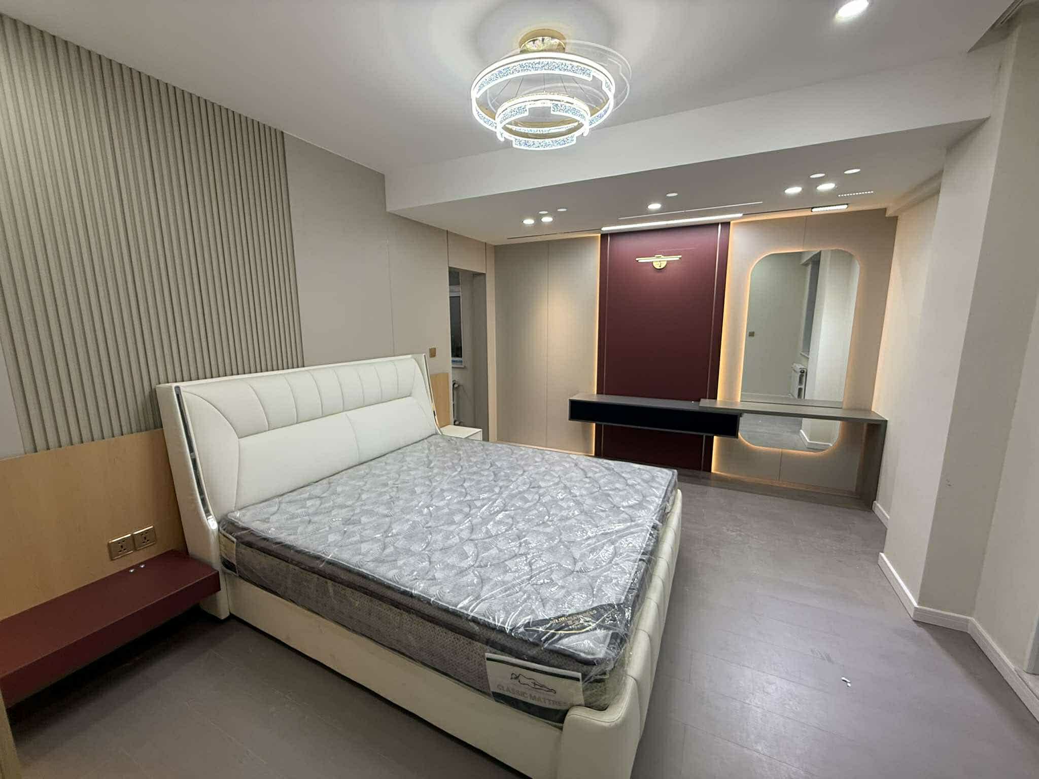 Master bedroom with white upholstered bed and crystal chandelier