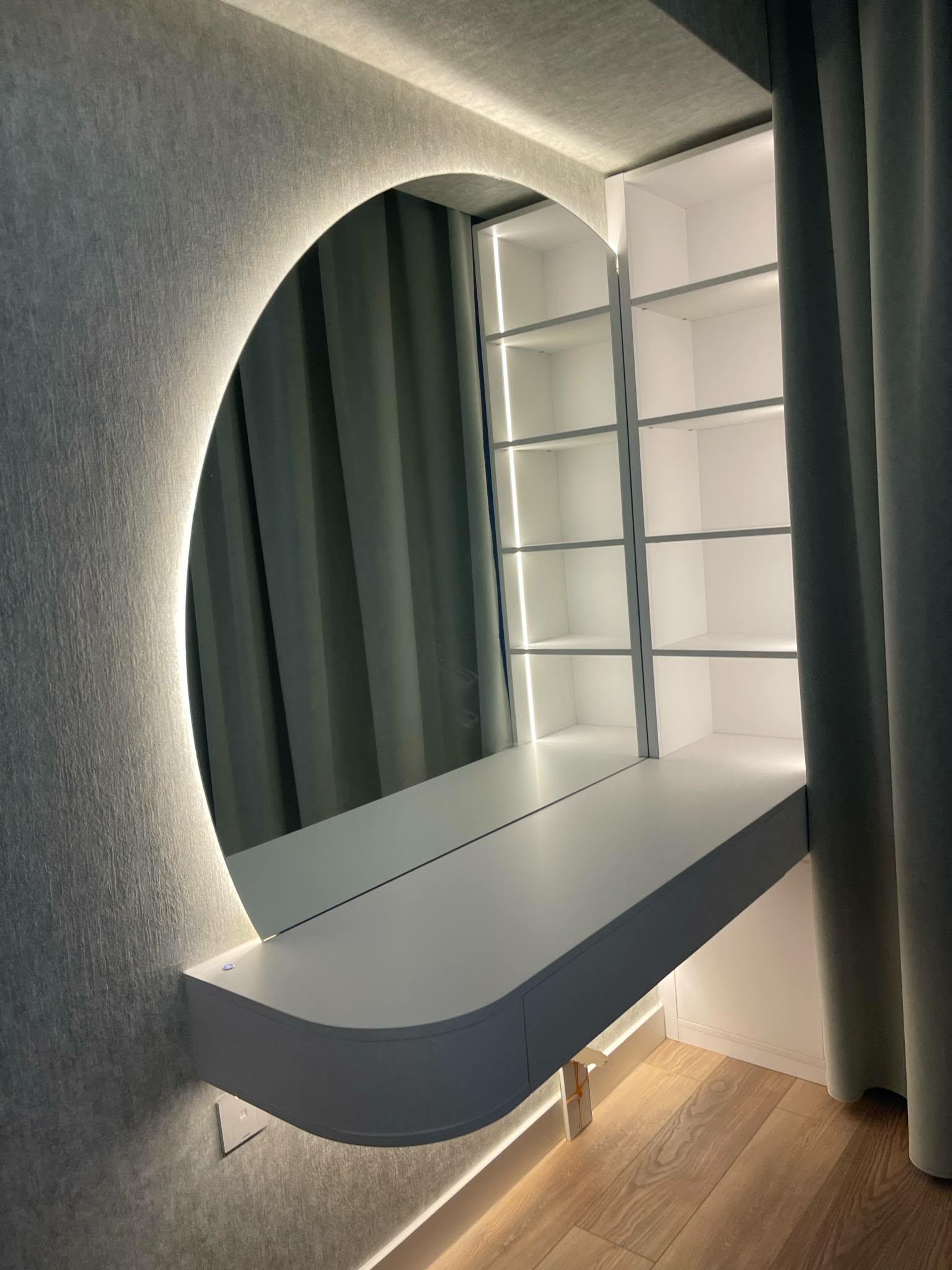 Vanity with backlit oval mirror and blue-grey shelf