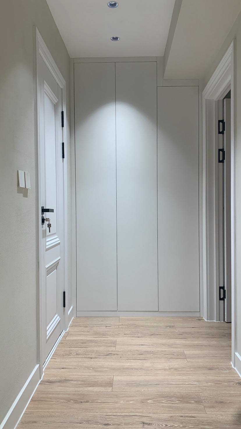 Slim corridor with full-height white wardrobe