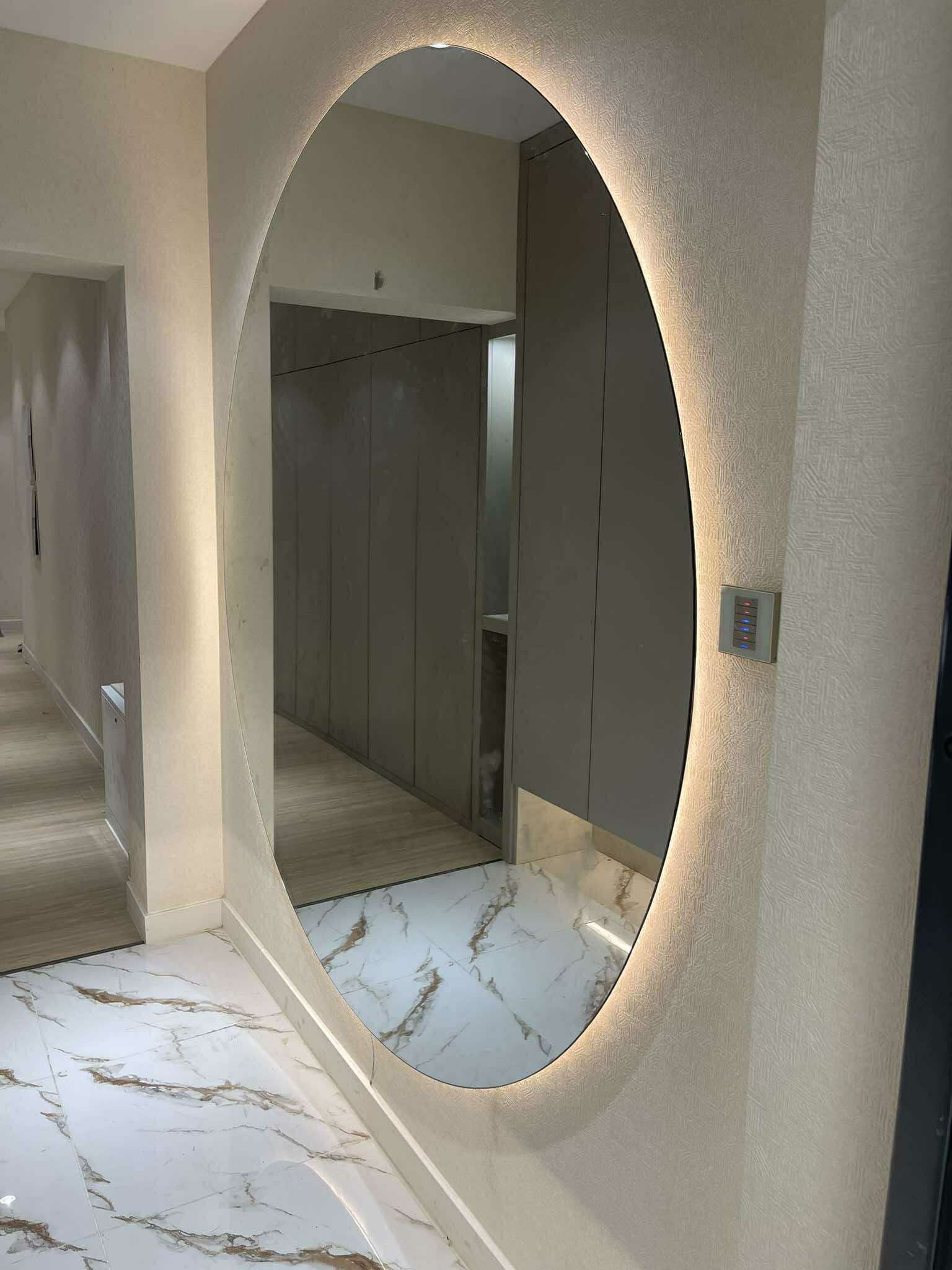 Oval backlit mirror in cream marble hallway