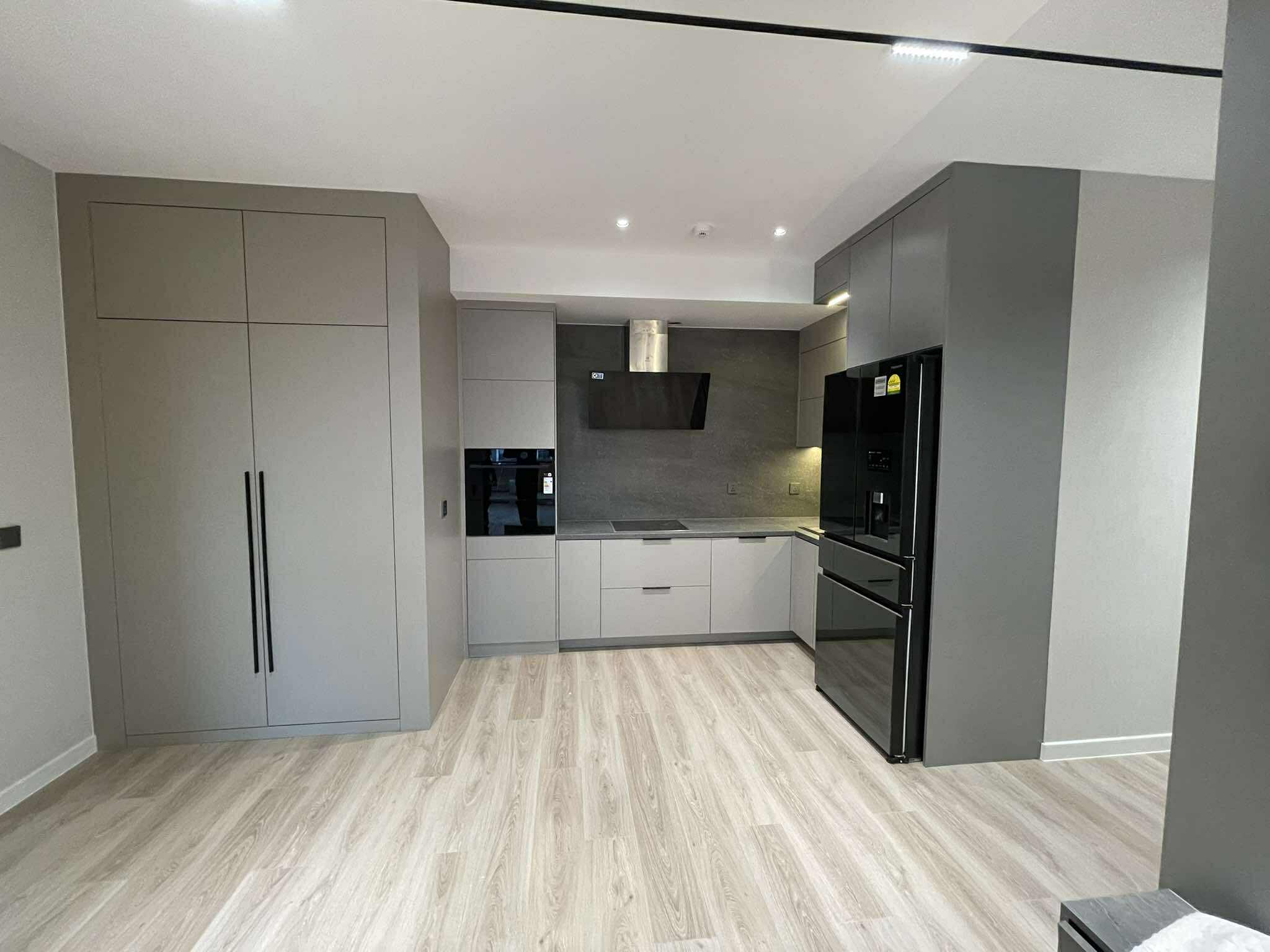 Grey L-shaped kitchen with black appliances