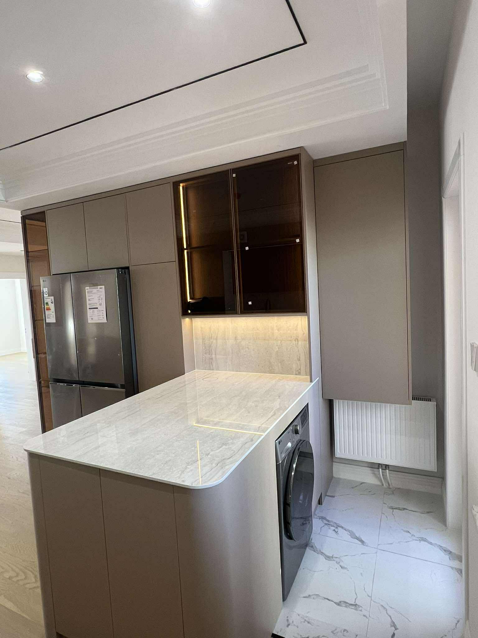 Taupe kitchen with marble island and glass upper cabinets