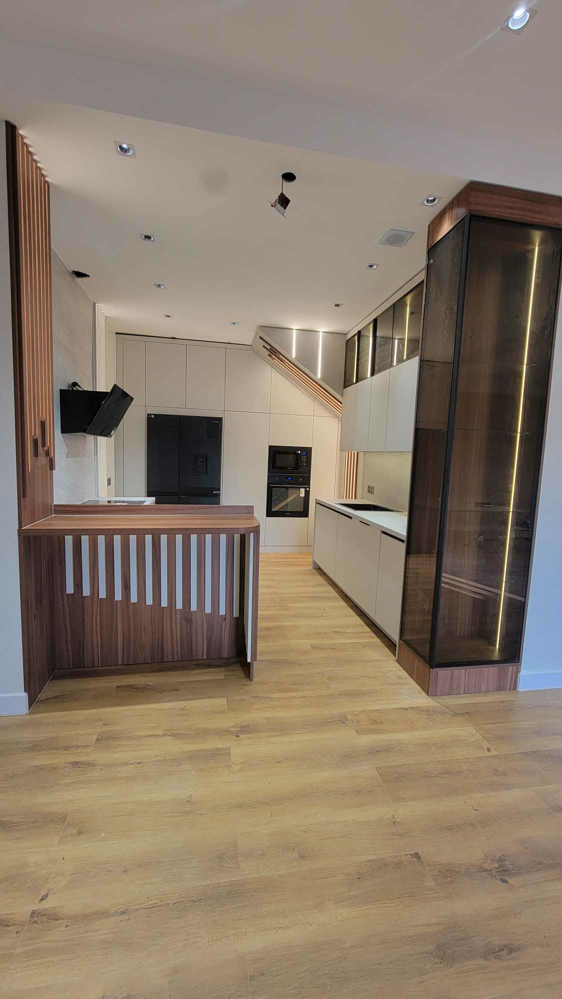 White kitchen with steel fridge and marble peninsula
